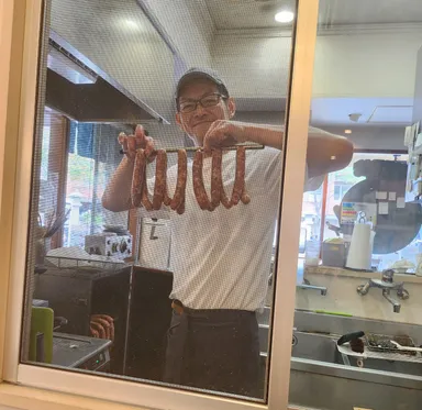 Owner of Samurai Sausage, holding new sausages.